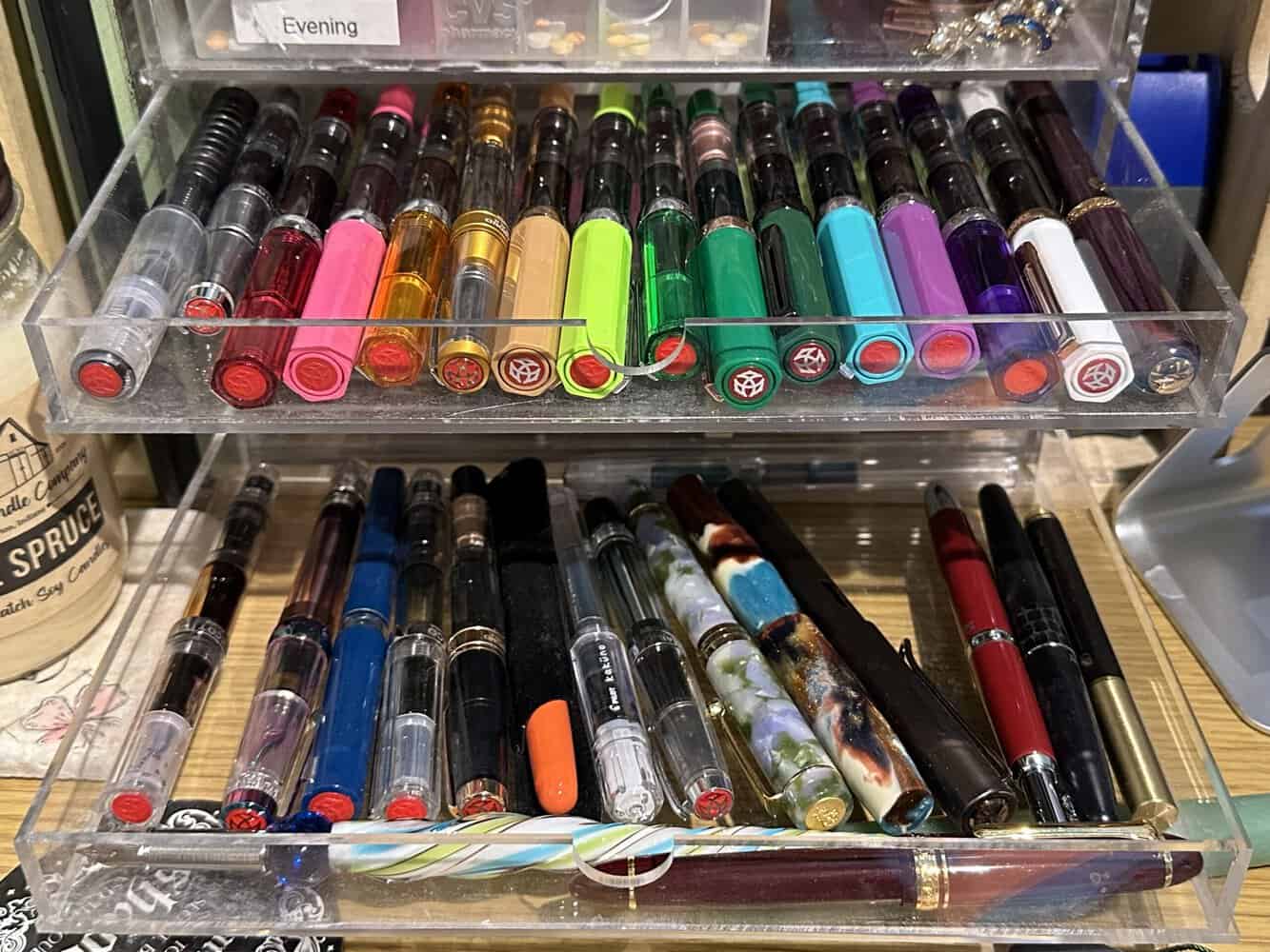Two clear acrylic drawers full of colorful fountain pens, half of which are TWSBI Eco pens.